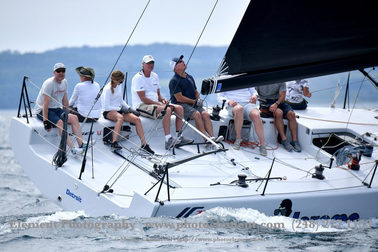 Crew sailing a yacht with a black sail named Detroit