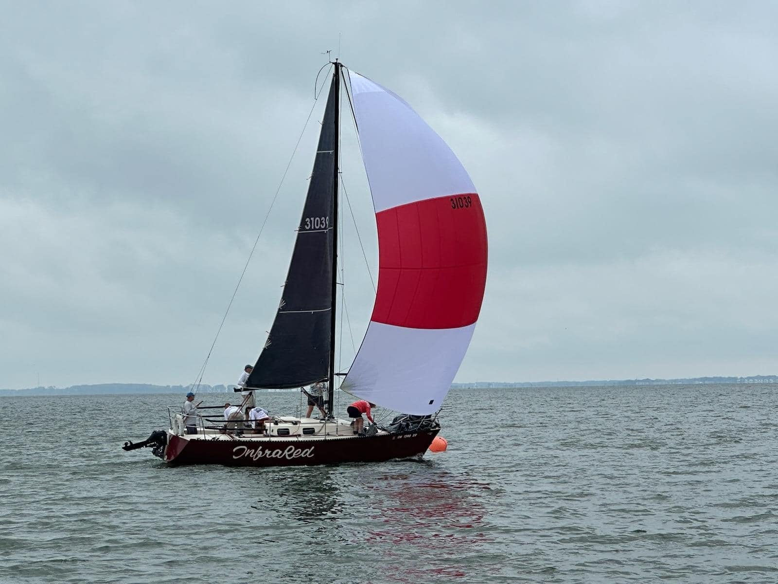 Sailboat with black and red-and-white sails on the water