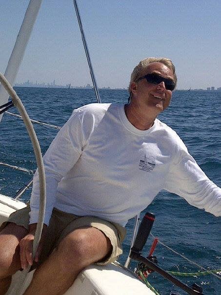 Person sailing on a sunny day, wearing sunglasses and a white shirt