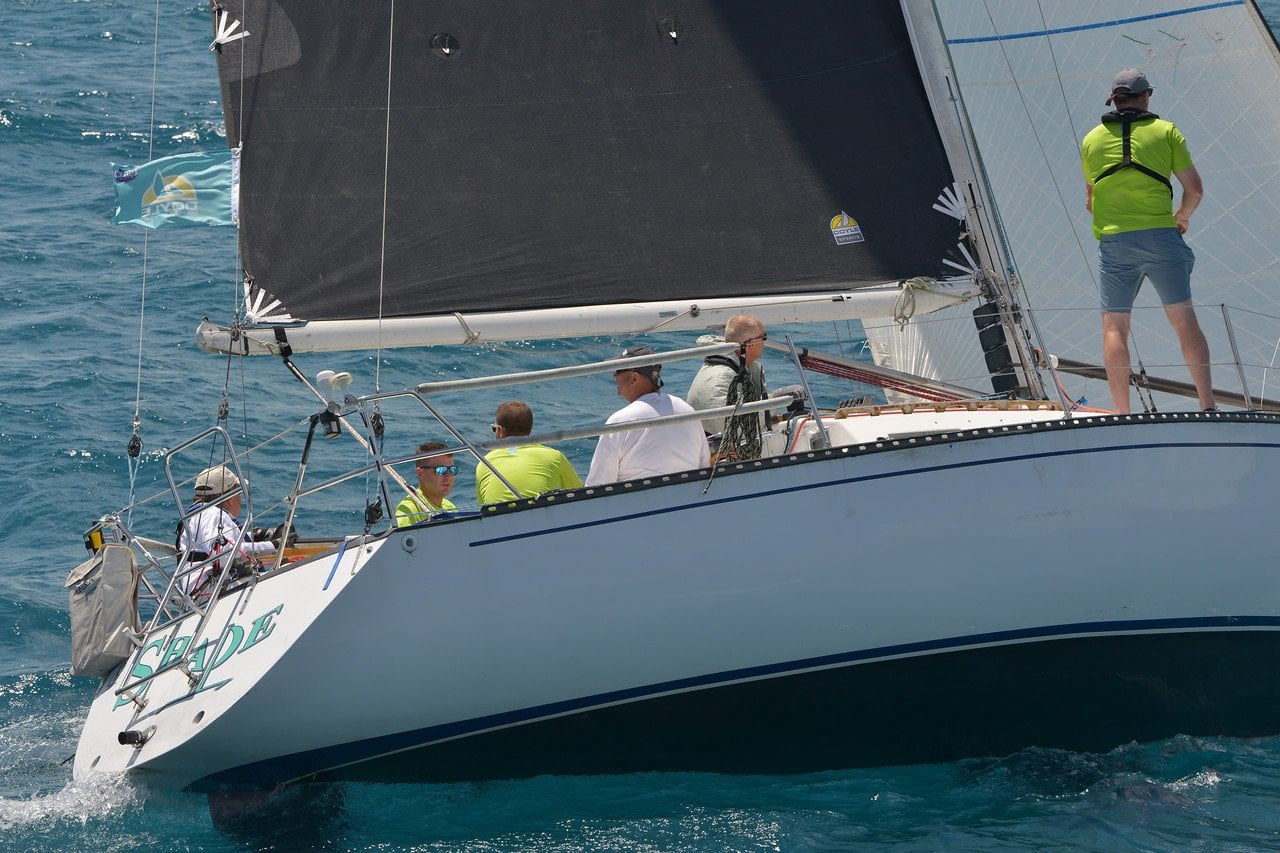 Sailboat with a black sail and crew in open water
