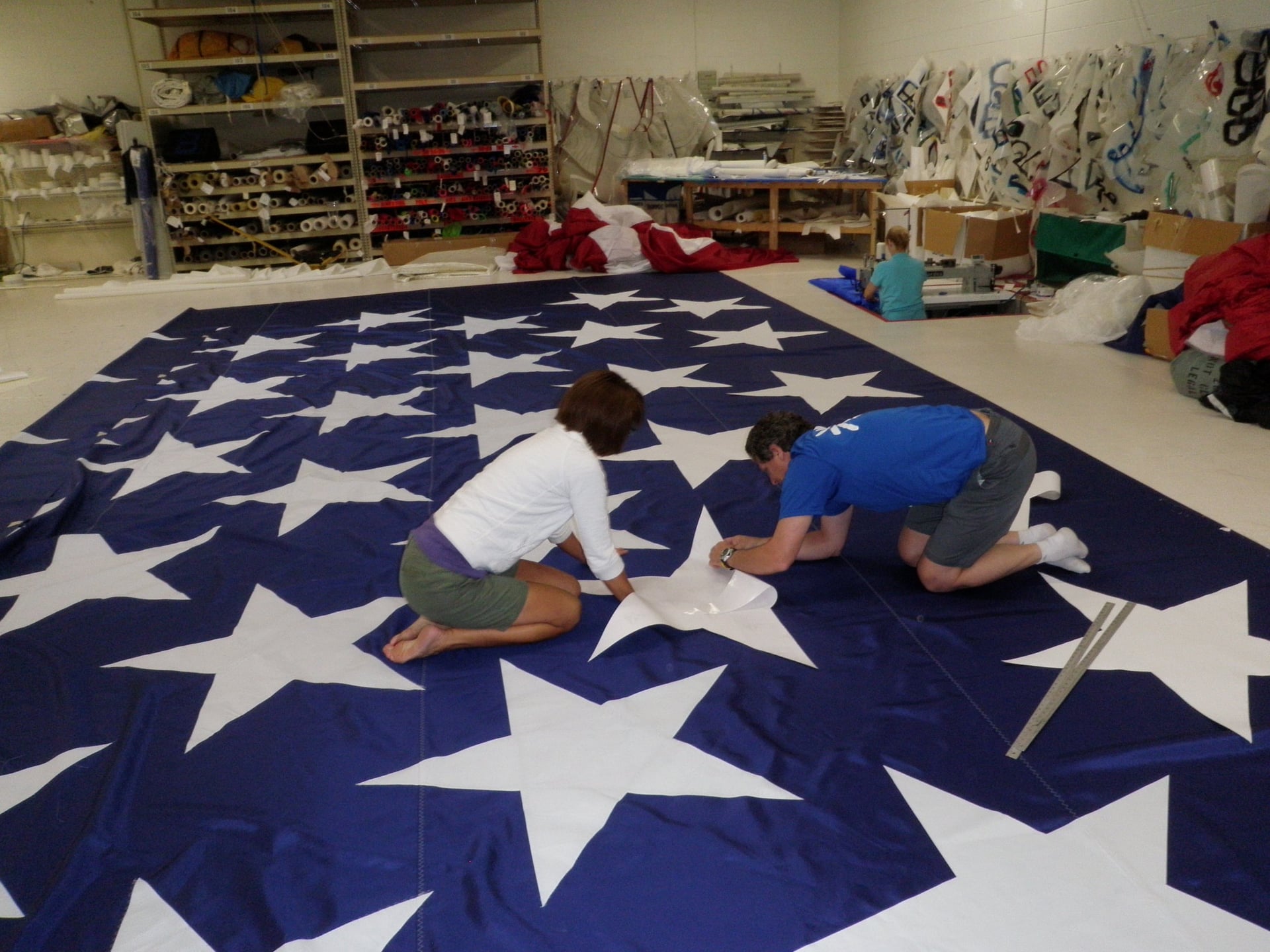 Two people working on a large starred flag in the workshop