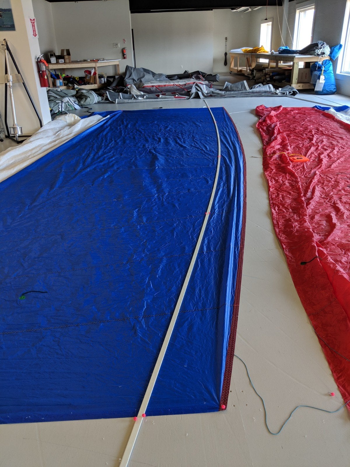Blue and red sails laid out on a workshop floor