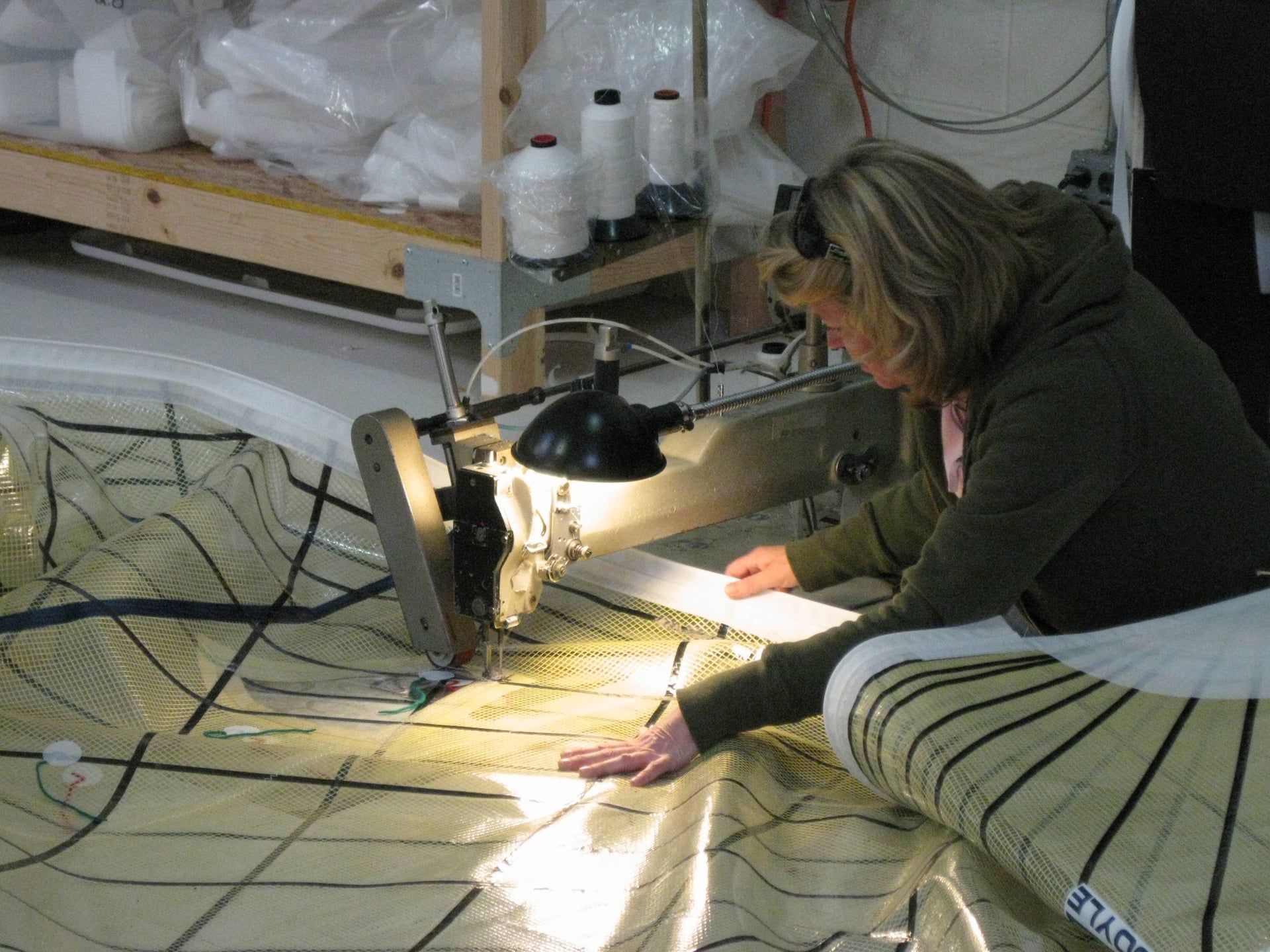 Person sewing a sail with a sewing machine in the workshop