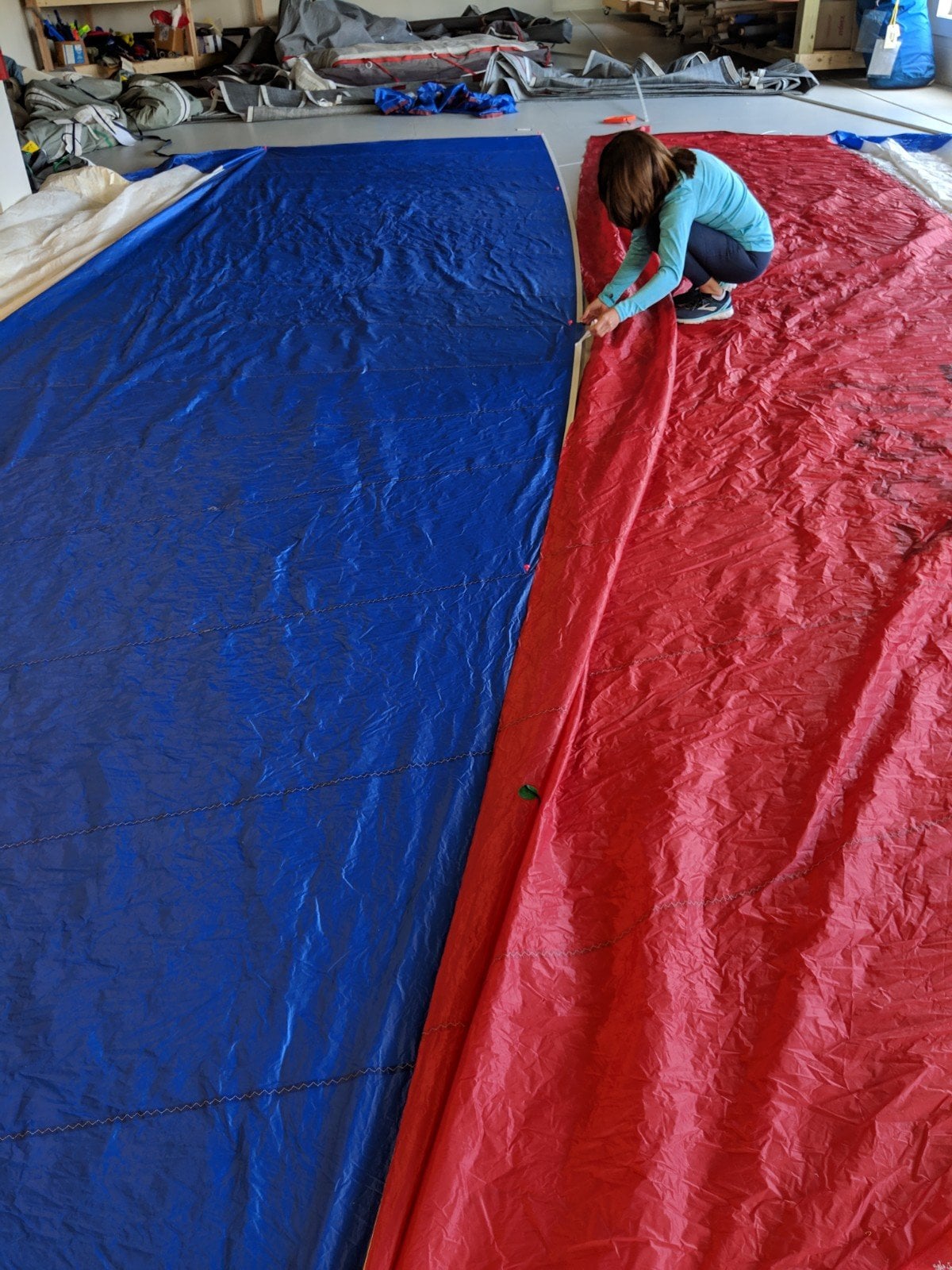 Person working on large blue and red fabric pieces