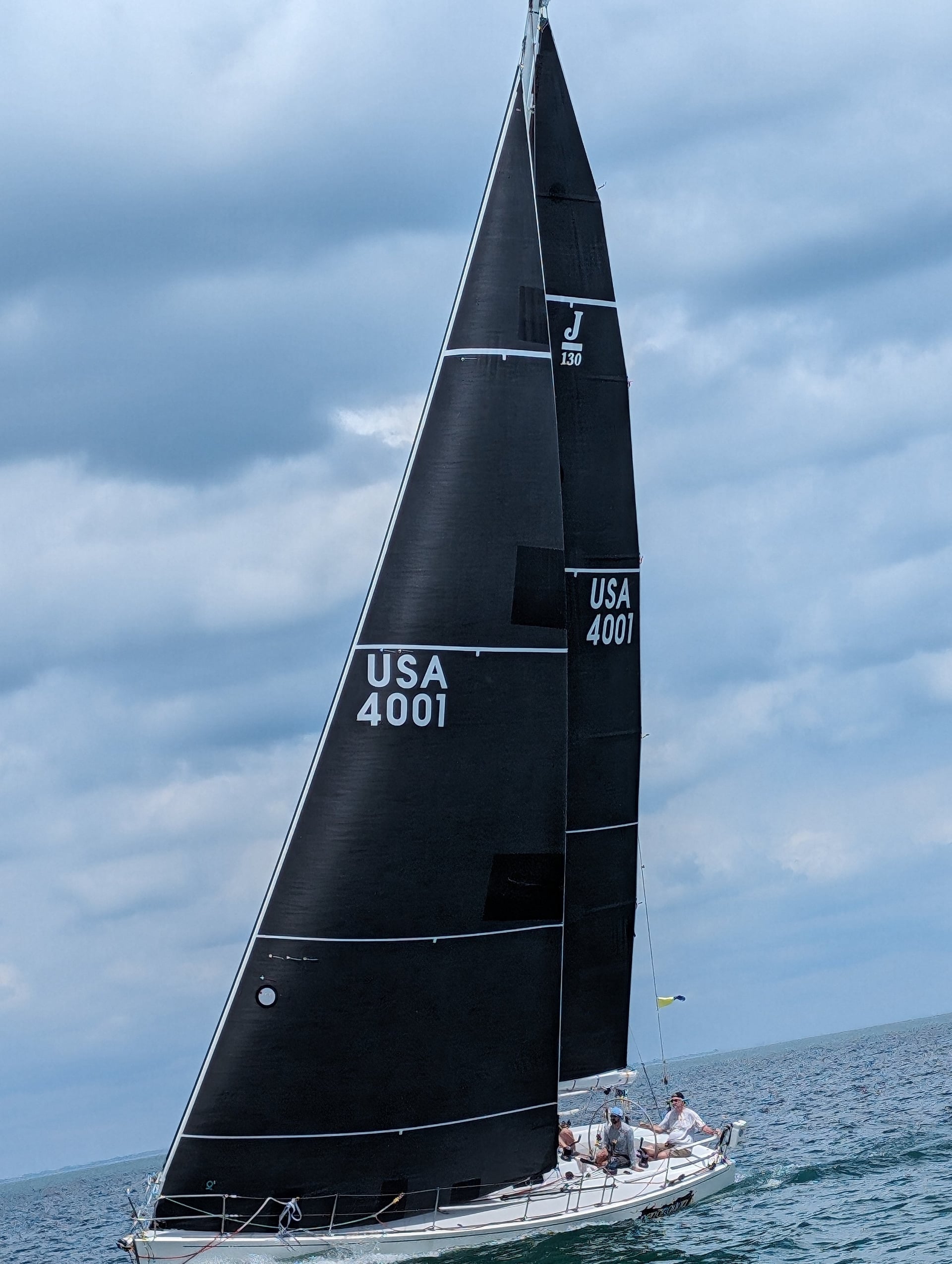 Sailboat with black sails on water, labeled USA 4001