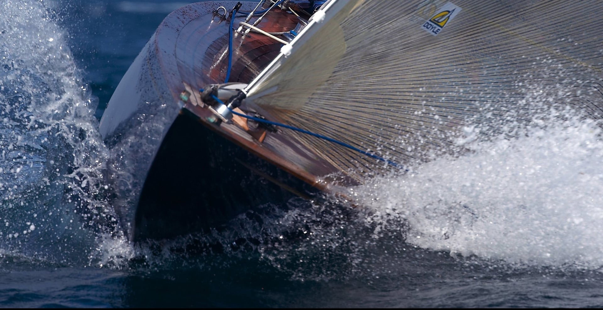 Sailboat bow cutting through water with a Doyle sail
