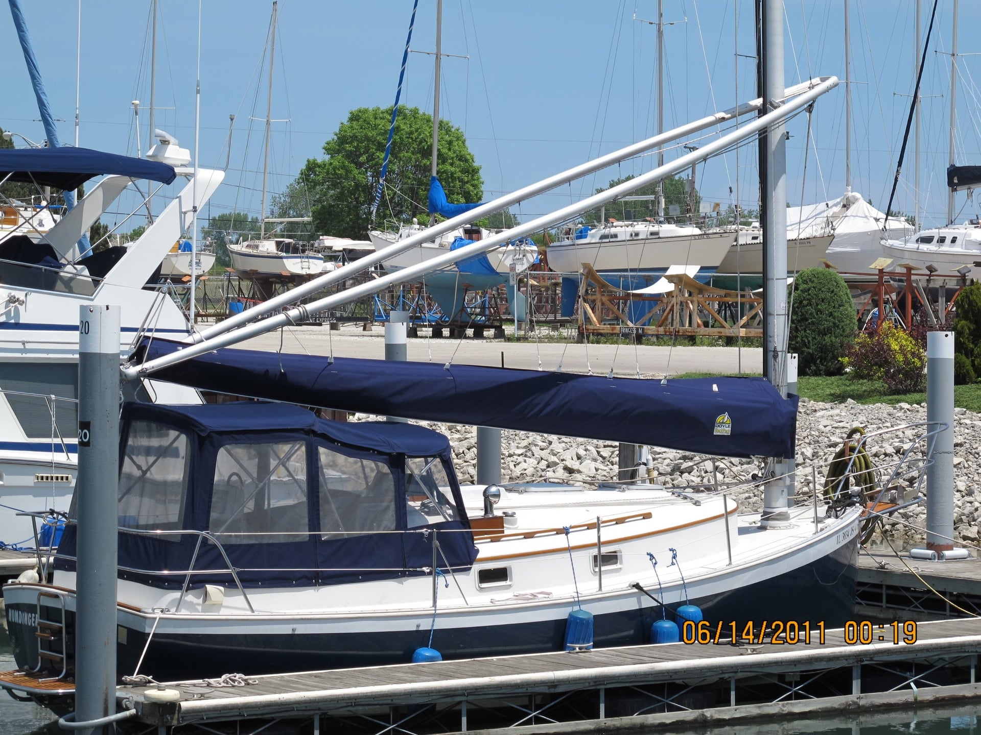 Sailboat docked in a marina with a blue cockpit cover