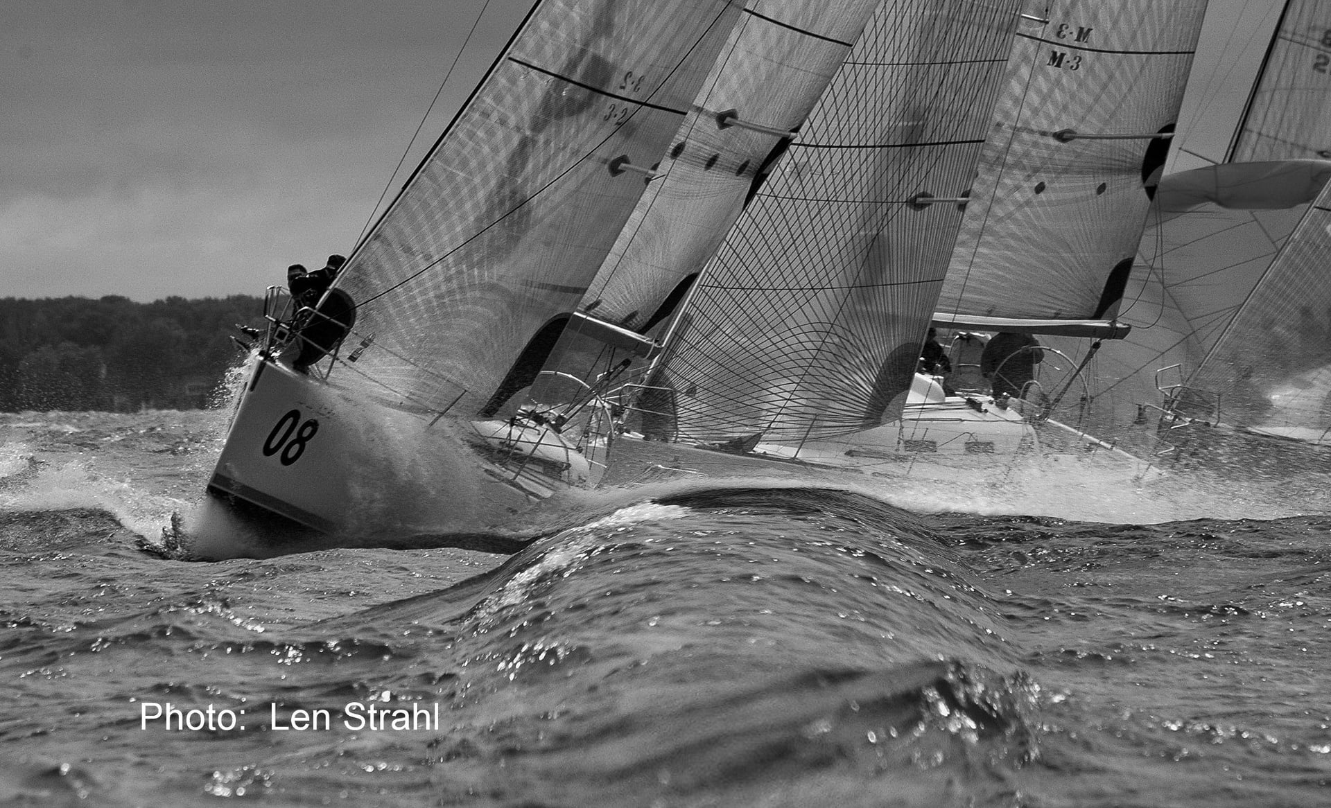 Black and white photo of a sailboat race in choppy water